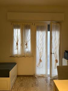 a room with two windows with white curtains at La casa di Tina in Briatico