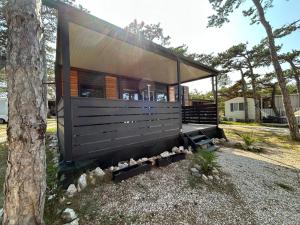 a small black house with a tree at Forest House Razanac in Ražanac
