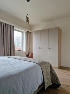 a bedroom with a bed with white cabinets and a window at Fully equiped 100 m2 appt with the perfect location in Vilvoorde