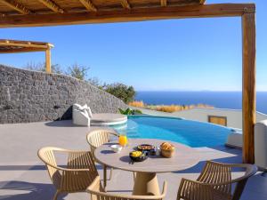 a patio with a table and chairs next to a swimming pool at Secret Path Luxury Villas in Imerovigli