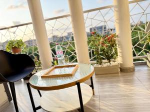 a glass table and chair on a balcony with plants at Julianah appart in Douala