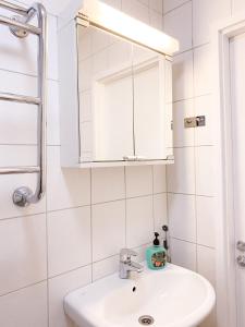 a white bathroom with a sink and a mirror at Studio Flamingo in Helsinki +2 photos