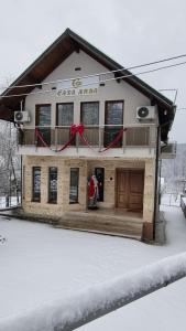 a house with a red bow on it in the snow at Casa Anda in Pucioasa