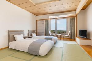 a hotel room with two beds and a television at KAMENOI HOTEL Aomori Makado in Noheji