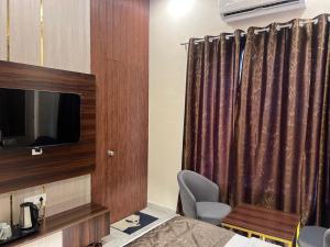 a room with a bed and a tv and a curtain at Hotel Highway Retreat in Gajraula