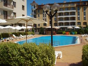 ein Schwimmbad mit Sonnenschirmen und Stühlen und ein Hotel in der Unterkunft Summer Breeze Apartments in Sonnenstrand