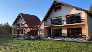 a house with people standing outside of it at Pensiunea Panoramic in Stațiunea Climaterică Sâmbăta