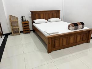 a bedroom with a wooden bed and a white floor at Thisha Hotel & Restaurant in Jaffna
