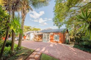 a brick house with palm trees and a driveway at Chateau B&B in Piet Retief