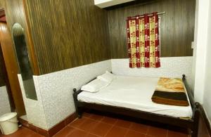 a small bed in a room with a window at Hotel Raj Palace in Jāmb