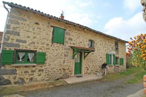 a stone house with green shutters and a horse standing outside at Familial 'le chiron' in Thiat