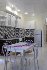 een keuken met een witte tafel en stoelen en een witte koelkast bij Apartment near Black Sea in Gelendzjik