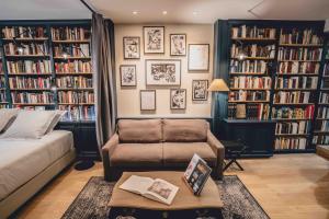 a living room with a couch and book shelves with books at La suite heart of le Marais - quartier des enfants rouges in Paris
