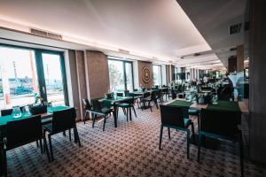 a restaurant with green tables and chairs and windows at Kongres Hotel Roca in Košice