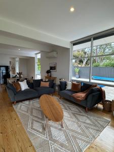 a living room with two couches and a table at Teringie Retreat with Breathtaking Views in Norton Summit
