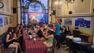 a group of people sitting at tables in a restaurant at Little Charm Hanoi Hostel in Hanoi
