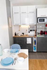 a kitchen with white cabinets and blue plates on a table at Studio Rive Royale in Viroflay