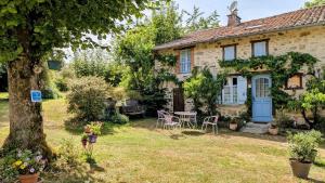 a cottage with a table and chairs in the yard at La ferme des souvenirs in Vaulry