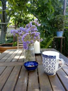 a table with a vase of purple flowers and a cup at Arcadia Guesthouse in Eresos