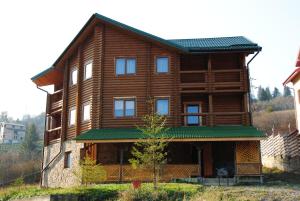 une grande maison en bois avec un toit vert dans l'établissement Крокус Мія, à Slavsko