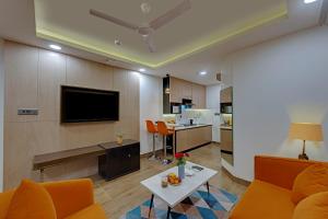 a living room with a couch and a tv and a kitchen at AR Suites Sohna Road in Gurgaon