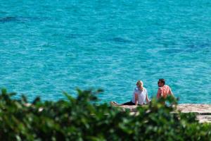 a man and woman sitting on a rock near the water at B&B Portorosso in Monopoli