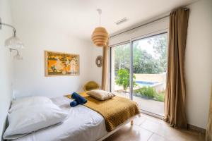 a bedroom with a bed and a large window at Maison Jeannot - Climatisée avec piscine in Vers Pont du Gard
