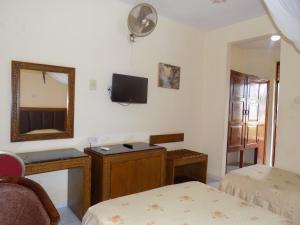 a room with two beds and a mirror and a tv at Hotel Oasis in Morogoro