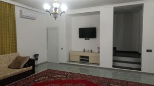a living room with a couch and a tv on a wall at Moy Dom in İsmayıllı