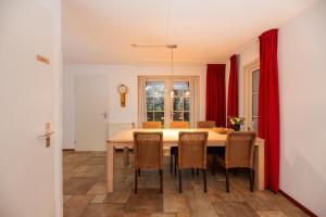 a dining room with a table with chairs and red curtains at Buitengoed het Lageveld 75 in Hoge-Hexel +52 photos
