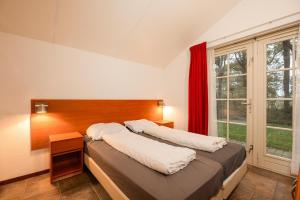 a bedroom with a large bed with a red window at Buitengoed het Lageveld 75 in Hoge-Hexel