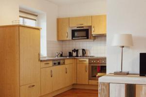 a kitchen with wooden cabinets and a microwave at Alpinresort Kaprun 3 in Kaprun