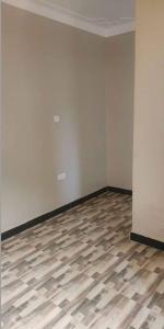 an empty room with a wooden floor and white walls at Jayson Housing in Wakiso