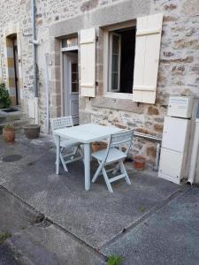 a white table and a chair in front of a building at Mémé jeanne in Ambazac +4 photos