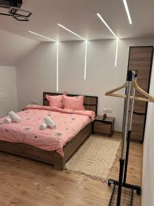 a bedroom with a large bed with pink sheets at The Forest Nest Apartment in Sărmaş