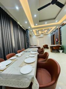 a long long table with chairs and plates on it at MK House in Greater Noida