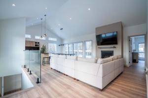 a living room with a white couch and a tv at Spa Pool Table & Comfort - Chalet le Barista in Brownsburg