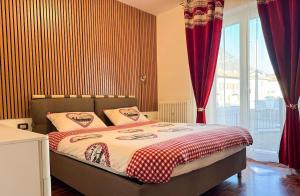 a bedroom with a large bed with red curtains at Nido Alpino - casetta con giardino, vista montagne in Tirano