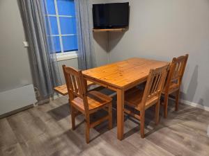 a wooden table with four chairs and a television at Vassel gård in Herand