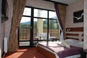 a bedroom with a bed and a large window at Chalet Zolota Pidkova&River 1 in Slavske