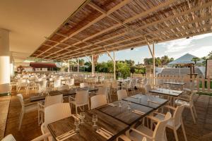 a restaurant with wooden tables and white chairs at Club Esse Sunbeach in Squillace