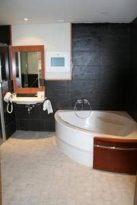 a bathroom with a bath tub and a sink at Alti Hôtel in Luchon
