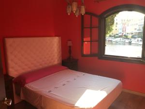 a bed in a red room with a window at Port Saplaya - Vistas al mar in Port Saplaya