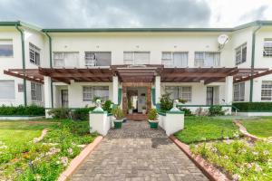 a large white building with a brick walkway at Fairway Holiday Accommodation in Hermanus