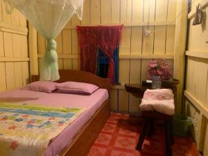 a small bedroom with a bed and a table at កុយ ឡាយ-Koy Lay in Chi Phat