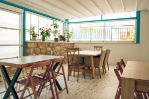 a dining room with tables and chairs and windows at ELPIDA Suites - Mandra, Greece in Mándra