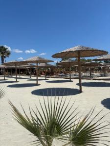 a beach with tables and umbrellas on the sand at ELPIDA Suites - Mandra, Greece in Mándra