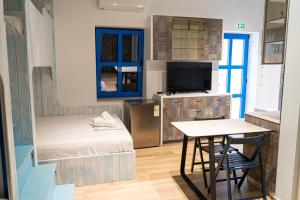 a bedroom with a bed and a table and a television at ELPIDA Suites - Mandra, Greece in Mándra +56 photos