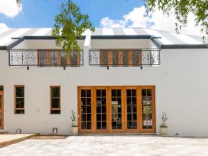 a white house with wooden doors and a balcony at The Tin Roof in Riebeek-Kasteel