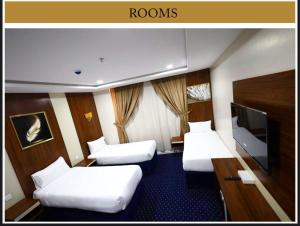 a hotel room with two beds and a flat screen tv at Maysan Al Mahbas Hotel in Al Khansāk